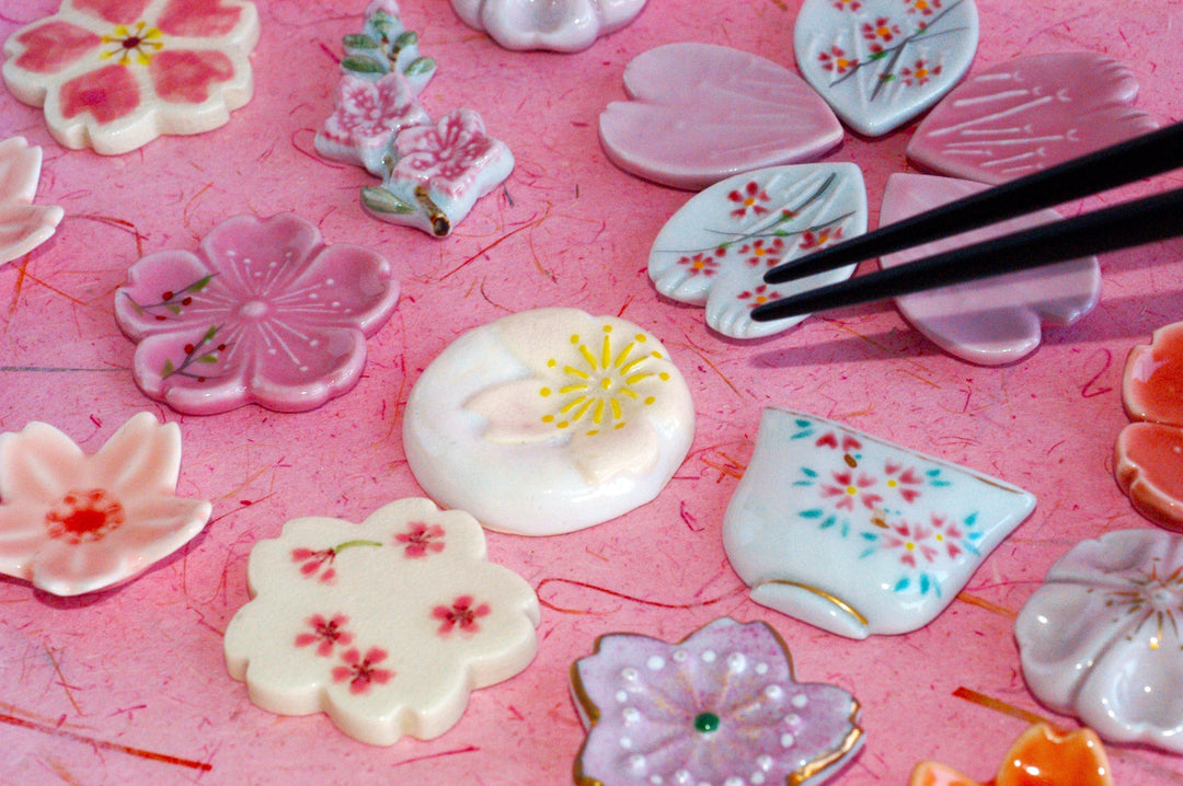 Black chopsticks placed on a cherry blossom-shaped chopstick rest among various sakura designs.