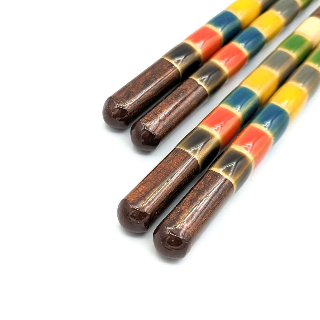  A close-up of two pairs of multicolored, dishwasher-safe Japanese chopsticks with rounded ends