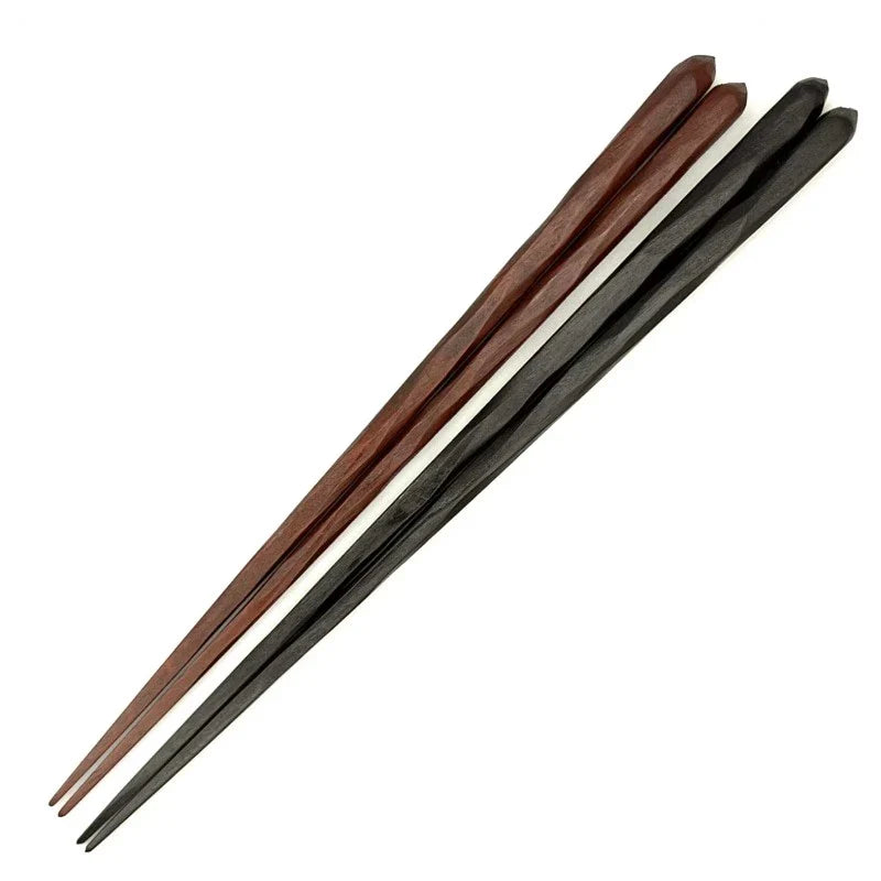 A close-up of a pair of rosewood chopsticks, one reddish-brown and one black, with a ridged design.