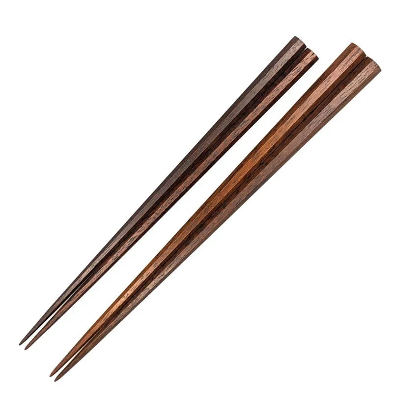  A close-up of a pair of handmade ironwood chopsticks, one dark brown and one lighter brown.