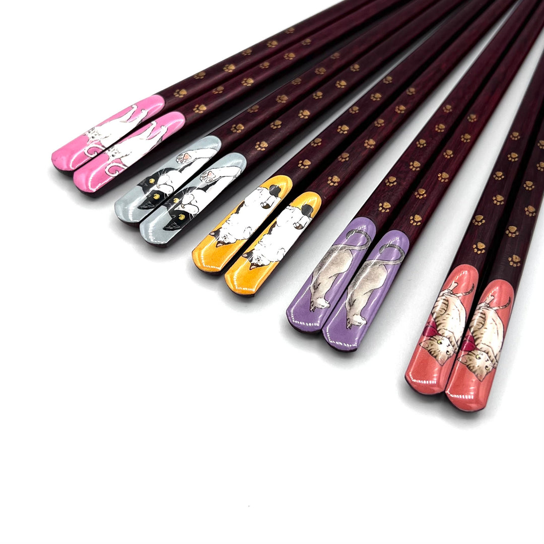 A set of playful Japanese chopsticks featuring cute cat illustrations, each with vibrant, colorful tips in pink, grey, yellow, purple, and orange. 